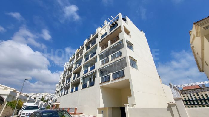 Corner Apartment – Benalmádena  Bright 2-bed, 2-bath second-floor apartment with separate east-facing kitchen, spacious living area, and large west-facing glass-enclosed terrace with sea and mountain views. Garage and community pool included.